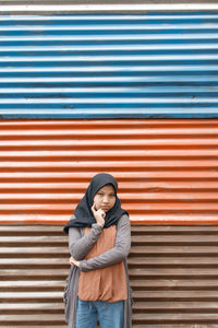 Portrait of girl standing against metal in city