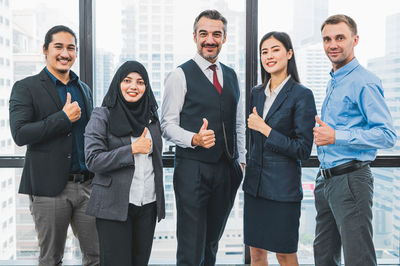 Portrait of business people standing against window