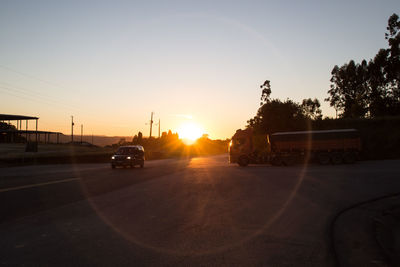 Vehicles on road at sunset