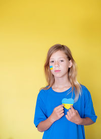Portrait of girl blowing bubbles against yellow background