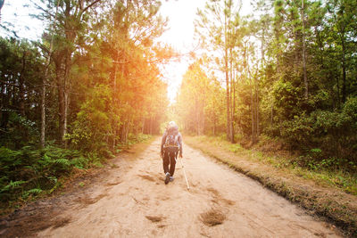 Rear view of man cycling on dirt road