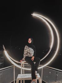 Full length of woman looking at illuminated railing