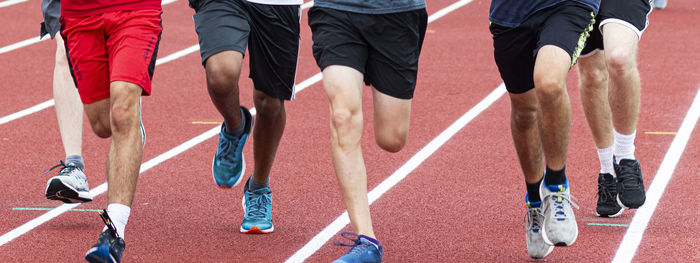 Close up of a group of high school runners running together on a track during practice.