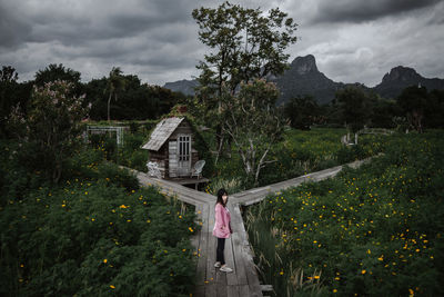 Woman standing by building against sky