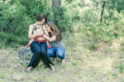 Full length of happy mother and daughter sitting on grass