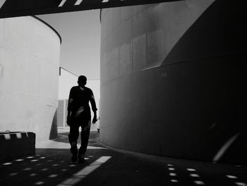 Rear view of man walking on footpath against building