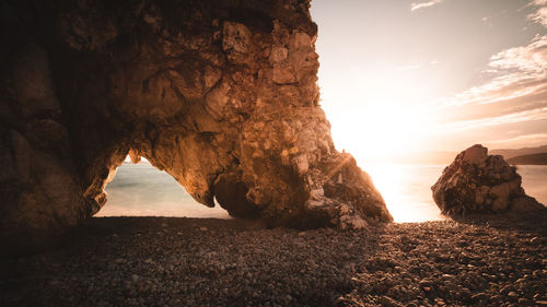 Rock formations by sea against sky during sunset