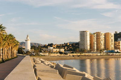 City buildings by river against sky