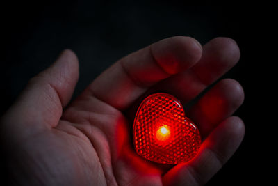 Cropped hand holding heart shape red light