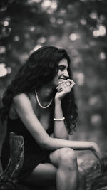 Portrait of young woman looking away while sitting in wild