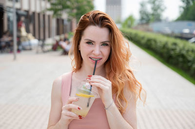 Portrait of a beautiful young woman drinking glasses outdoors