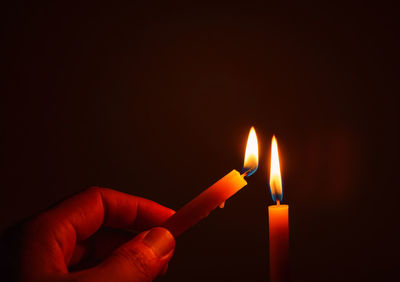 Close-up of hand holding burning candle