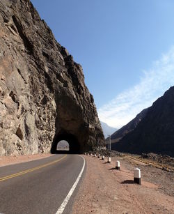 Road tunnel by mountain against sky