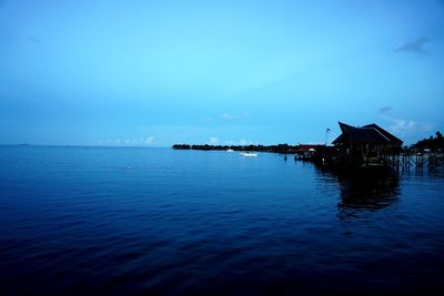 Scenic view of sea by building against blue sky