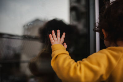 Rear view of child hand on window