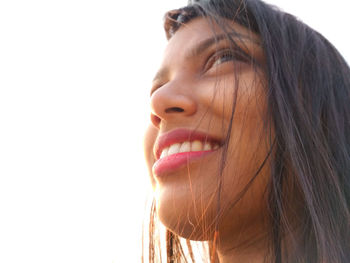 Close-up low angle view of smiling woman looking away against sky