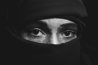 Portrait of young woman against black background