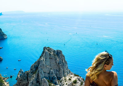 Woman by sea against blue sky