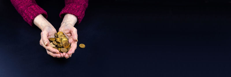 Close-up of hand holding apple against black background