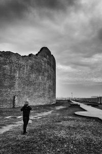 Rear view of man standing on rock against sky