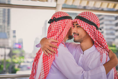 Smiling businessman embracing colleague on elevated road in city