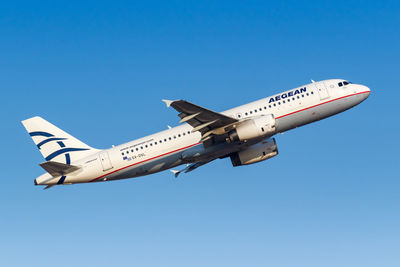 Low angle view of airplane flying against clear blue sky