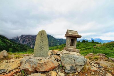 Stones on mountain against cloudy sky