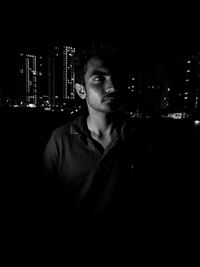 Portrait of young man standing in city at night