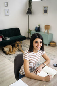 Portrait of smiling young woman using mobile phone at home