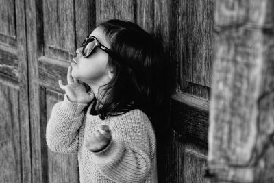 Side view of woman looking away against wall