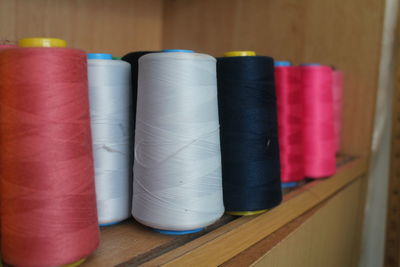 Close-up of multi colored thread spools on shelf