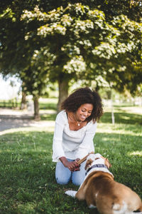 Smiling mid adult woman holding stick while playing with dog at park