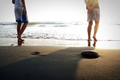 Low section of man standing on beach