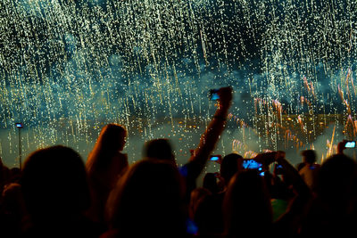 Crowd watching firework display at night