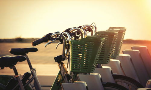Close-up of bicycle in basket against sea during sunset