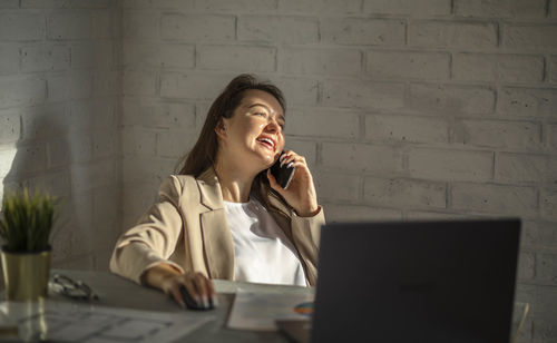 Optimism of young entrepreneur, moment of joyful connectivity, backdrop of modern workspace.