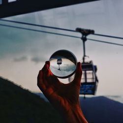 Close-up of person holding umbrella against sky