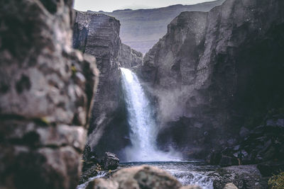 Scenic view of waterfall amidst mountains