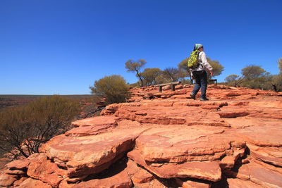 Man on rock against clear blue sky