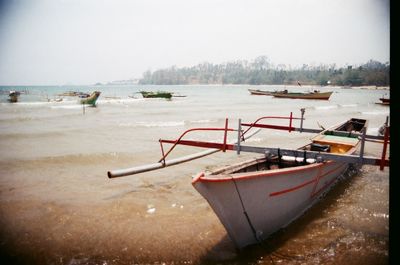 Boats moored on beach against clear sky