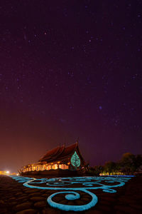 Illuminated building against blue sky at night