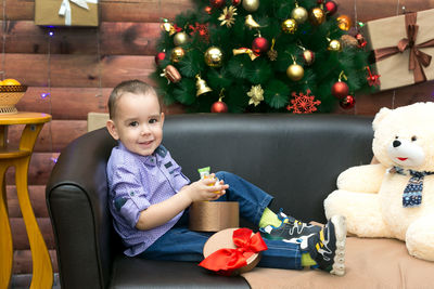 A little boy has opened and is looking at a new year gift a box of sweets.