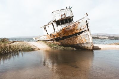 Abandoned ship in sea against sky