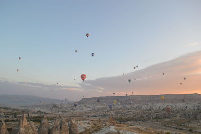 Hot air balloons flying over landscape against sky during sunrise