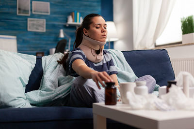 Sick young woman holding bottle at home