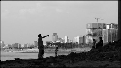 People standing on beach against buildings in city