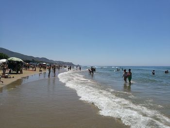 People on beach against clear sky