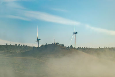 Wind turbines on land against sky