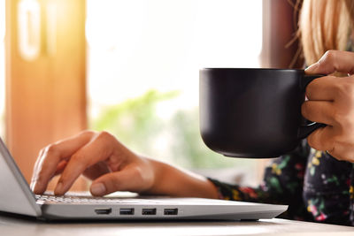Midsection of woman using laptop on table