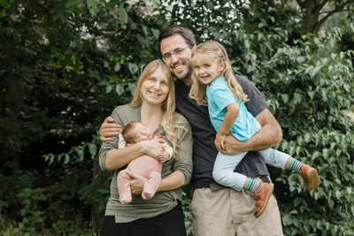 Full length of a smiling boy with daughter against trees